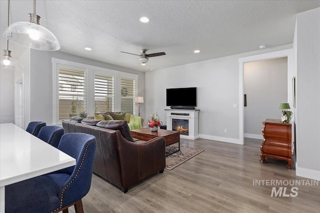 300 S Adventure Way, Kuna, ID 83634 - living room with a textured ceiling, light wood-type flooring, ceiling fan, recessed lighting, and a glass covered fireplace