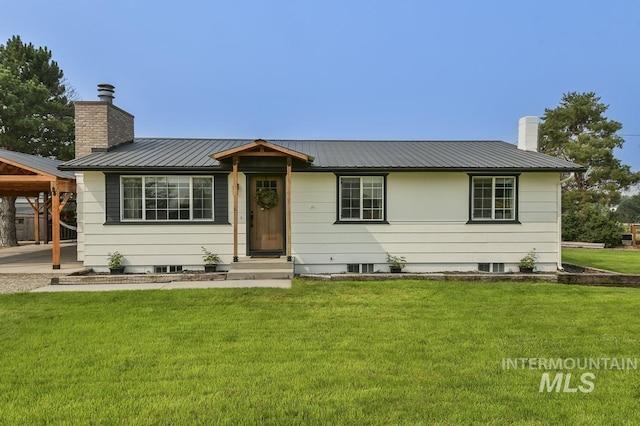 single story home with a chimney, a carport, a front yard, and metal roof
