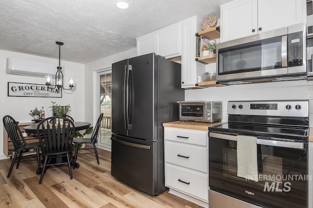kitchen featuring open shelves, a textured ceiling, a chandelier, stainless steel appliances, and light wood finished floors