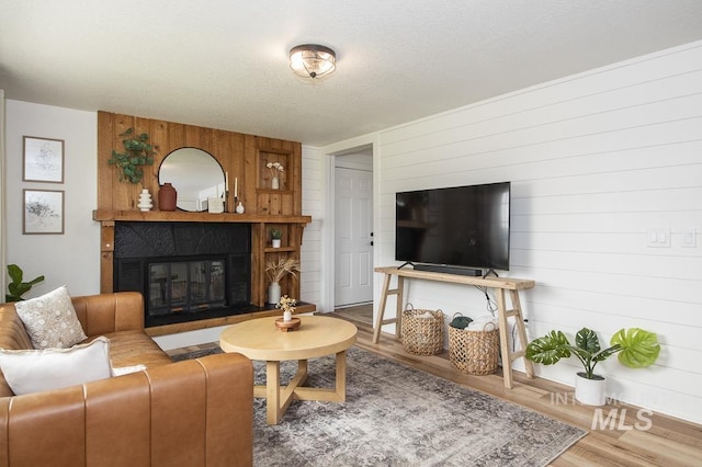 living area featuring wood walls, wood finished floors, and a tile fireplace