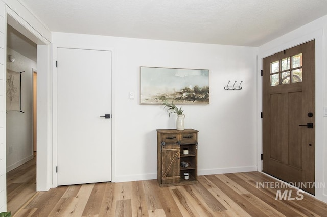 foyer with light wood-type flooring and baseboards