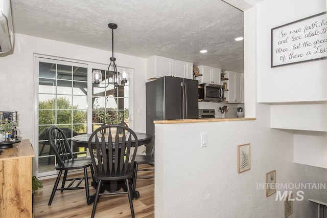 dining room with recessed lighting, wood finished floors, a textured ceiling, and an inviting chandelier