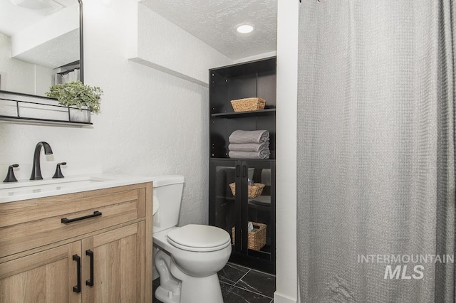 bathroom featuring vanity, a textured ceiling, and toilet