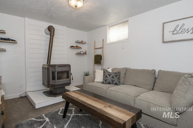 living area featuring a textured ceiling, carpet, a wood stove, and baseboards
