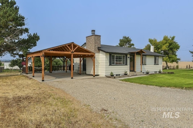 view of front of property with a front lawn, a chimney, a gazebo, and metal roof