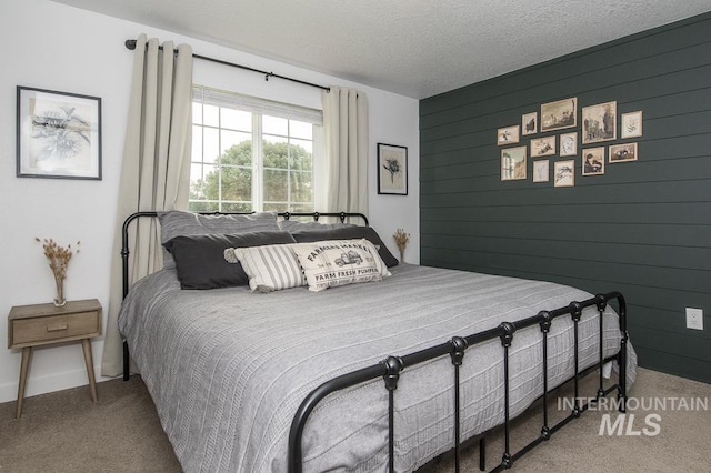 bedroom with wood walls, baseboards, carpet flooring, and a textured ceiling
