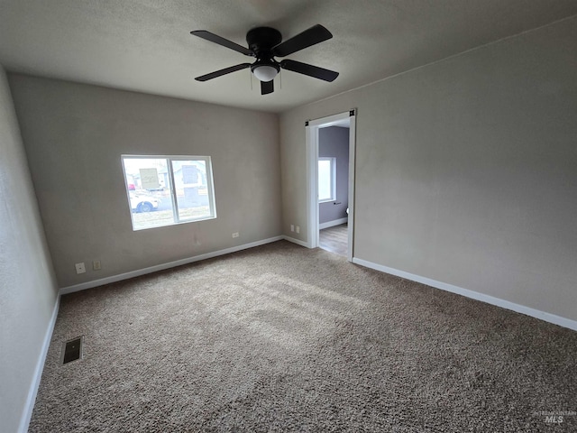 spare room featuring a textured ceiling, carpet flooring, visible vents, and baseboards