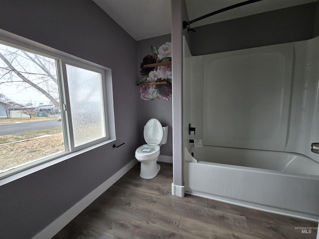 bathroom with washtub / shower combination, wood finished floors, toilet, and baseboards