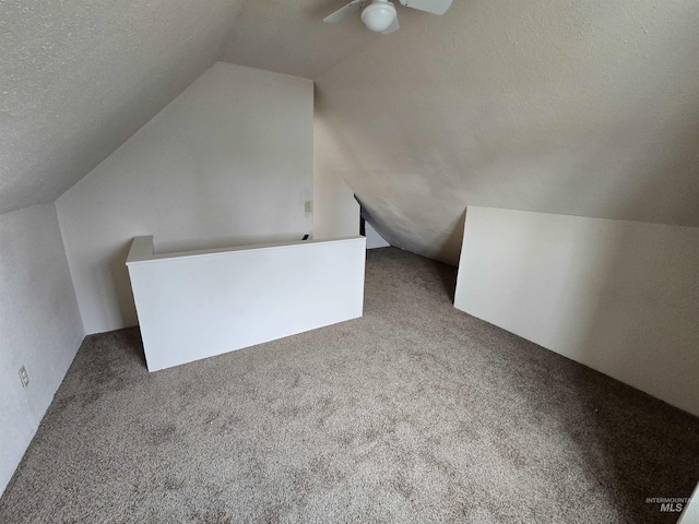 bonus room featuring ceiling fan, carpet, vaulted ceiling, and a textured ceiling