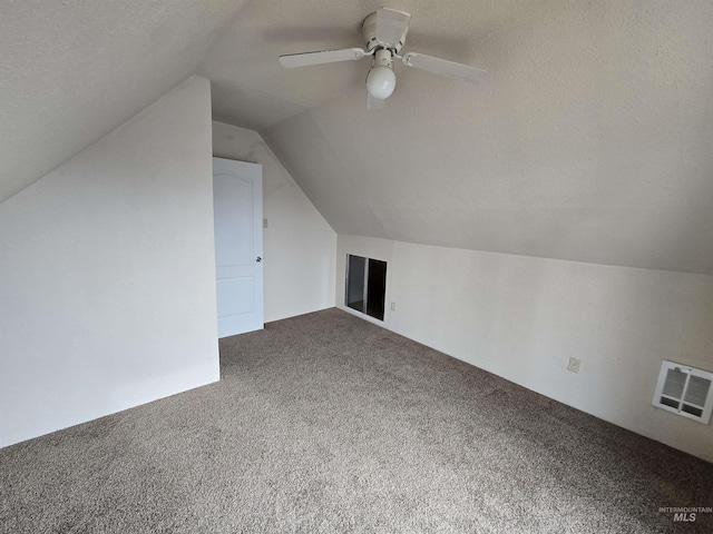 bonus room featuring visible vents, a ceiling fan, carpet flooring, vaulted ceiling, and a textured ceiling