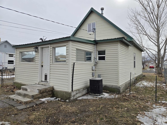 rear view of house with metal roof, fence, and central AC unit