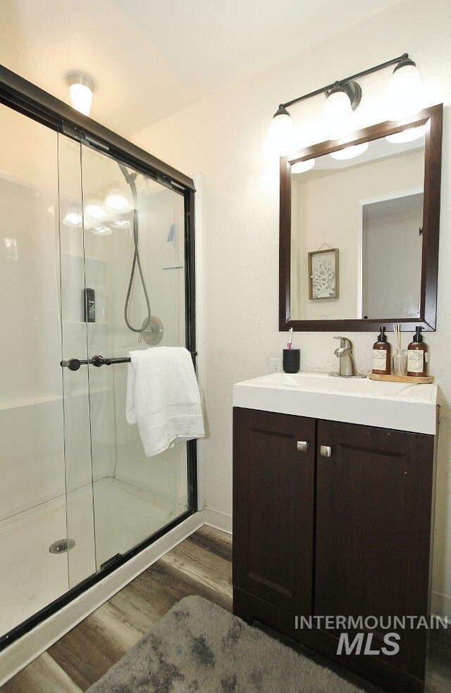 bathroom with wood-type flooring, vanity, and a shower with door