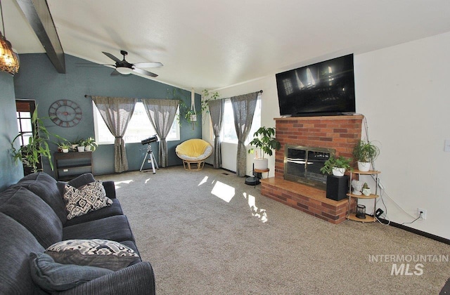 living room featuring ceiling fan, vaulted ceiling with beams, a fireplace, and carpet flooring