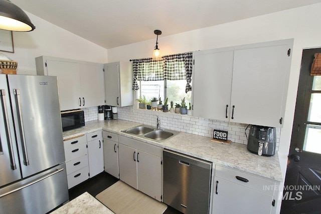 kitchen with tasteful backsplash, sink, vaulted ceiling, hanging light fixtures, and appliances with stainless steel finishes