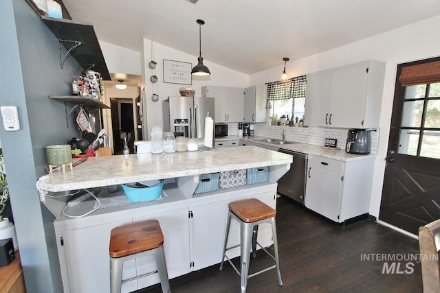 kitchen with a kitchen breakfast bar, decorative backsplash, stainless steel appliances, decorative light fixtures, and dark hardwood / wood-style floors