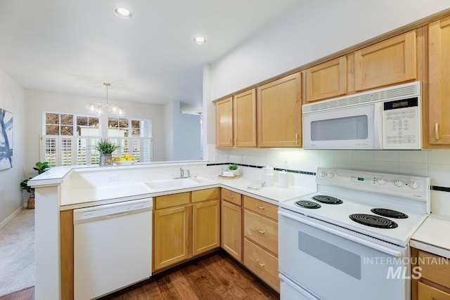 kitchen with white appliances, sink, decorative light fixtures, dark hardwood / wood-style flooring, and kitchen peninsula