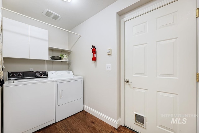 washroom with separate washer and dryer, cabinets, and dark wood-type flooring