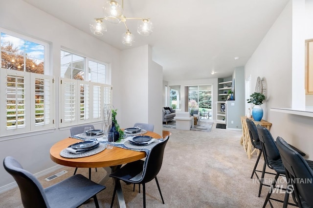 carpeted dining room with a chandelier