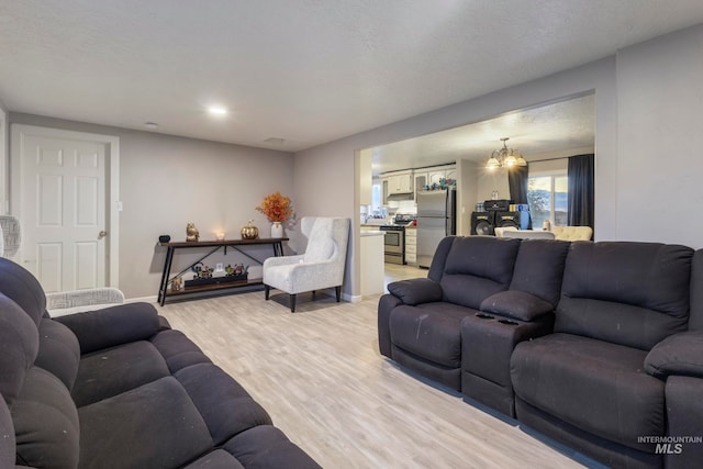 living room featuring a chandelier, a textured ceiling, and light wood-type flooring