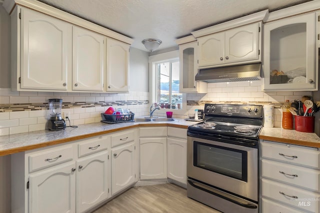 kitchen with backsplash, electric stove, and white cabinetry