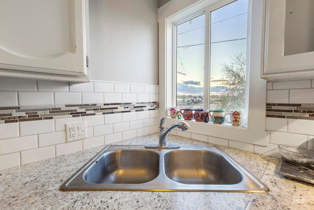 kitchen featuring decorative backsplash, white cabinetry, a healthy amount of sunlight, and sink