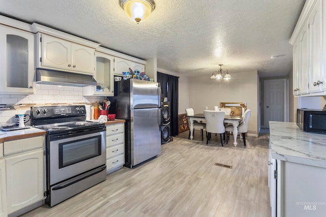 kitchen with appliances with stainless steel finishes, light wood-type flooring, pendant lighting, white cabinets, and a chandelier