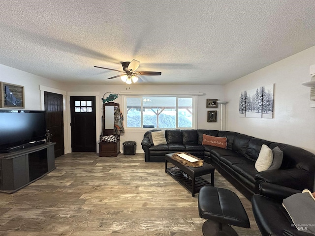 living room with a textured ceiling, wood finished floors, and a ceiling fan