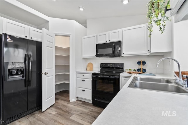 kitchen featuring white cabinetry, black appliances, light countertops, and a sink