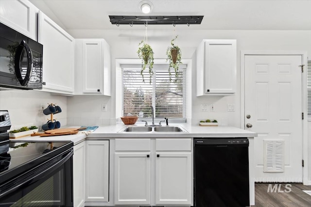 kitchen with white cabinetry, black appliances, light countertops, and a sink