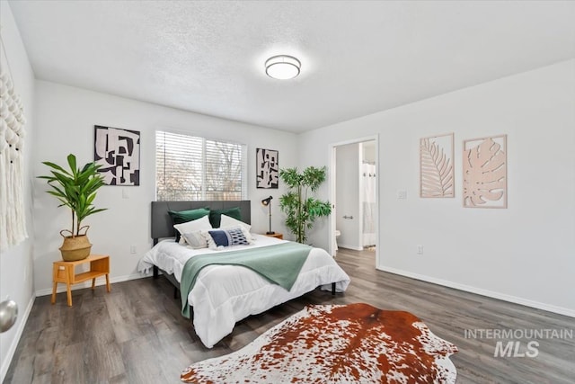 bedroom with connected bathroom, wood finished floors, baseboards, and a textured ceiling