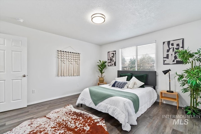 bedroom featuring wood finished floors, baseboards, and a textured ceiling