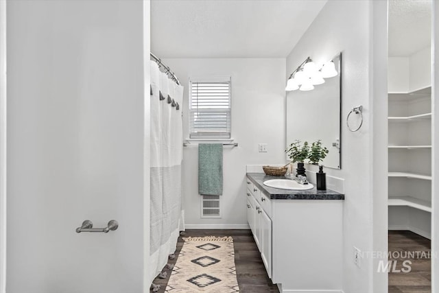 bathroom with visible vents, wood finished floors, a shower with shower curtain, baseboards, and vanity