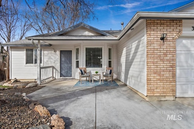 exterior space with a porch, an attached garage, and brick siding