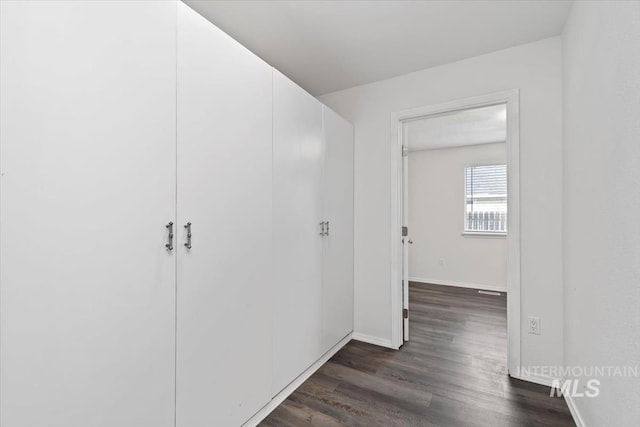 hall featuring baseboards and dark wood-style flooring