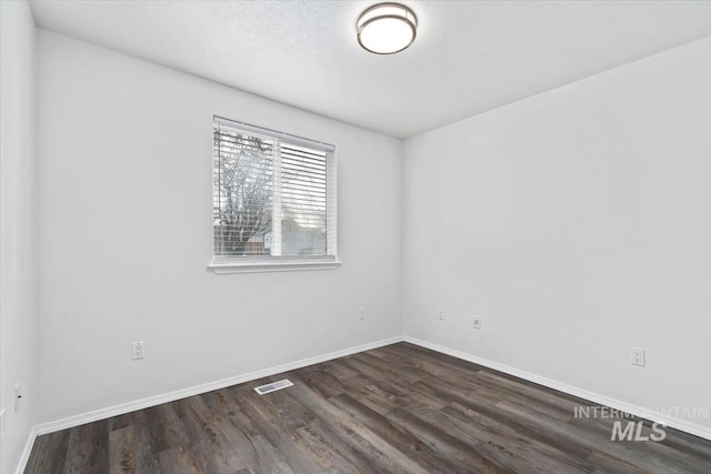 unfurnished room featuring wood finished floors, visible vents, and baseboards