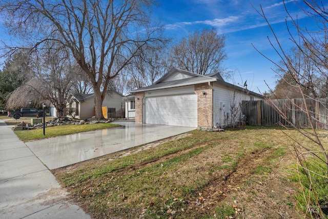 view of home's exterior with brick siding, an attached garage, fence, a lawn, and driveway