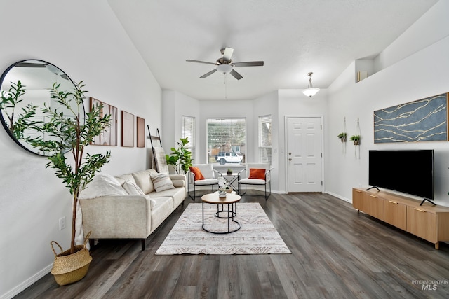 living area with a ceiling fan, baseboards, and dark wood-style flooring