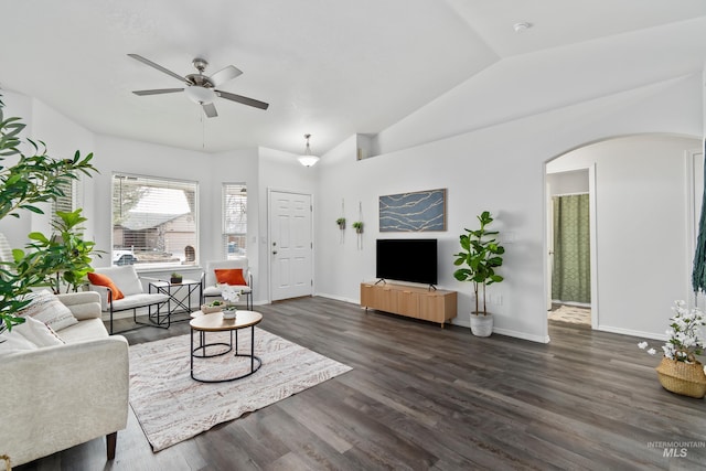 living room featuring baseboards, dark wood finished floors, arched walkways, ceiling fan, and vaulted ceiling