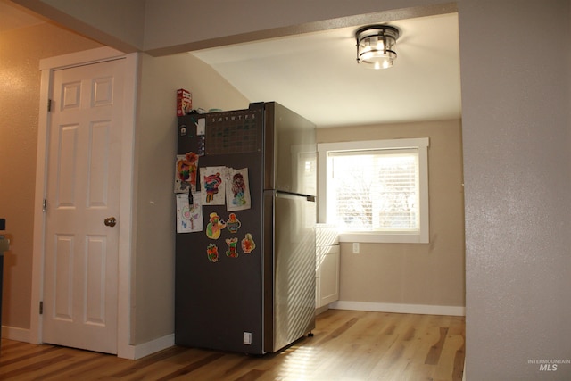 kitchen featuring vaulted ceiling, light hardwood / wood-style flooring, and stainless steel refrigerator