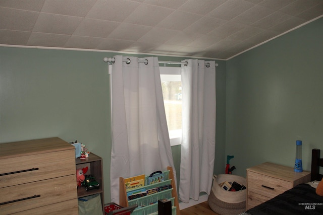 bedroom with ornamental molding and hardwood / wood-style floors