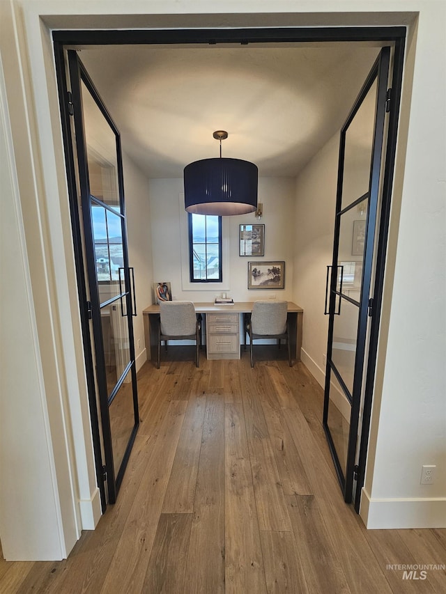 corridor with hardwood / wood-style floors and baseboards