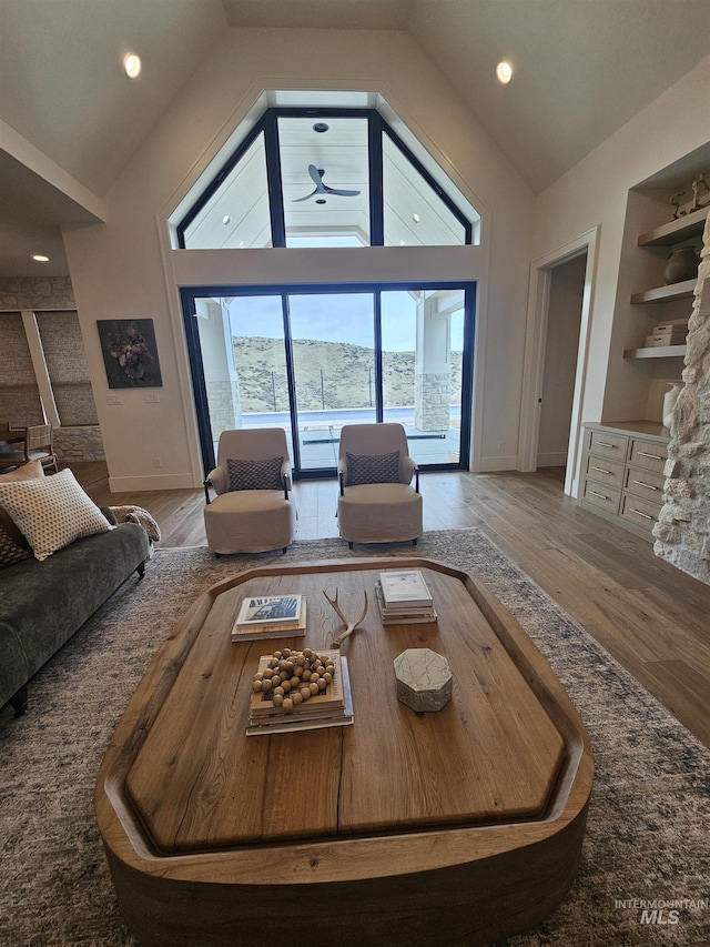 living area featuring wood finished floors, recessed lighting, high vaulted ceiling, and baseboards