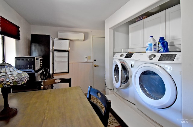 washroom featuring a wall mounted air conditioner, washer and dryer, and cabinets