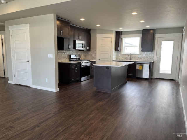 kitchen featuring a center island, dark wood-style flooring, stainless steel appliances, light countertops, and baseboards