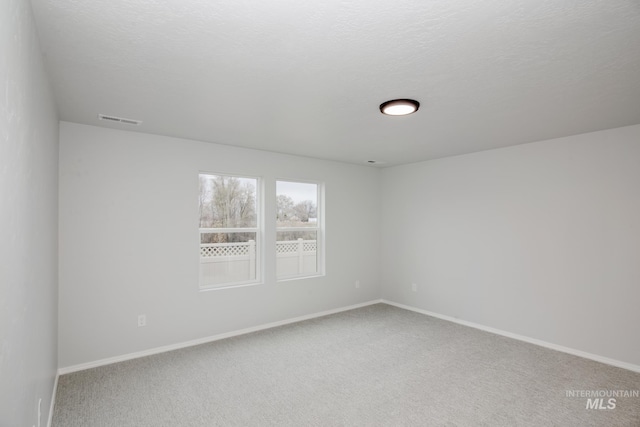 carpeted spare room featuring a textured ceiling