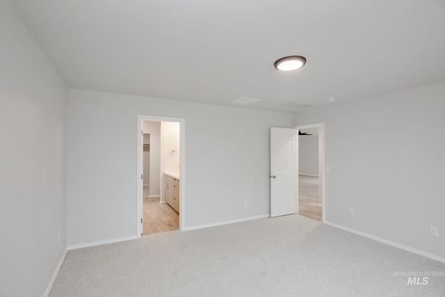 unfurnished bedroom featuring light colored carpet and ensuite bathroom