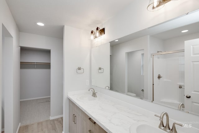 bathroom featuring vanity, toilet, a shower with door, and wood-type flooring