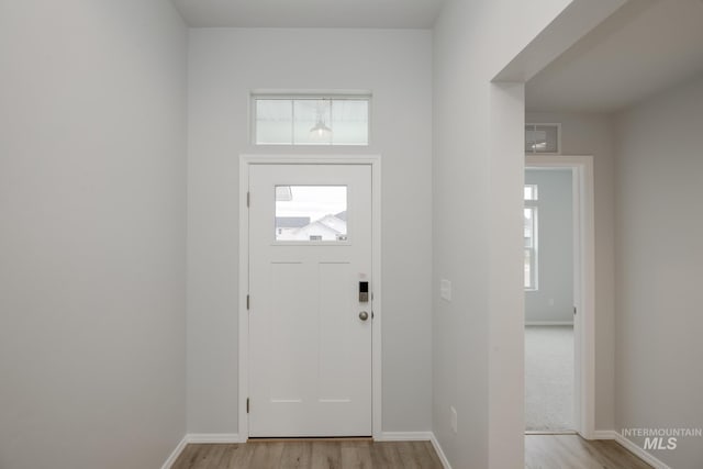 foyer entrance with a wealth of natural light, baseboards, and light wood finished floors