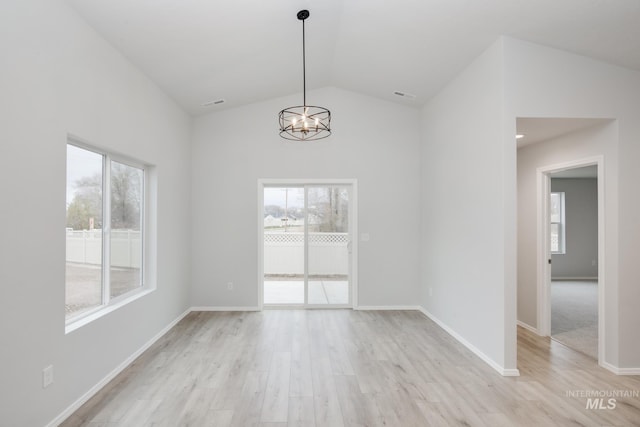 unfurnished dining area with a chandelier, light hardwood / wood-style flooring, and lofted ceiling