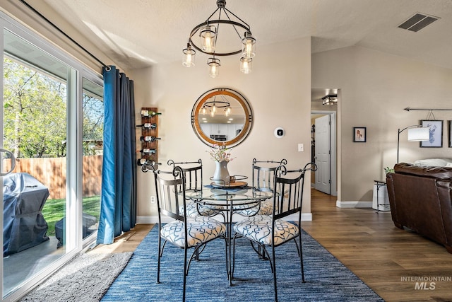 dining area with baseboards, wood finished floors, visible vents, and vaulted ceiling